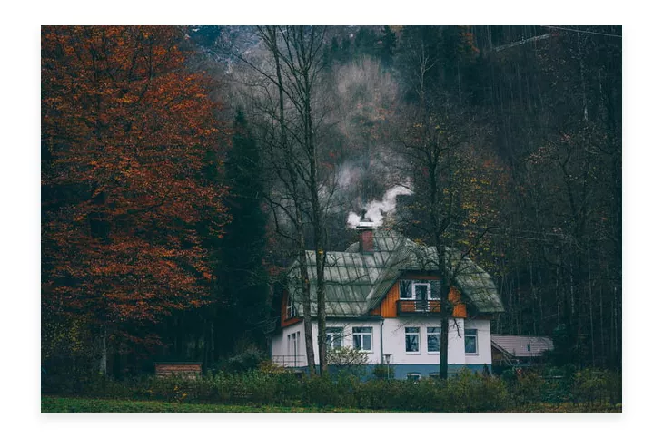house with chimney located in the middle of the forest