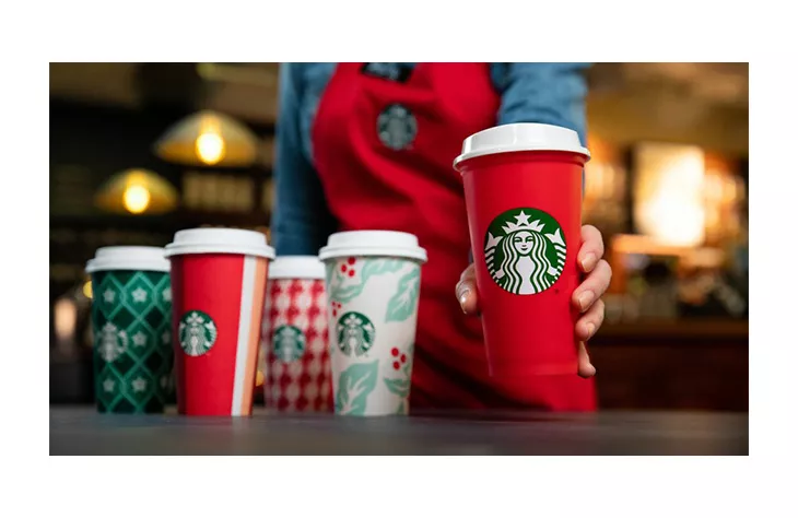 Barista serving coffee in Starbuck's famous red holiday cup.